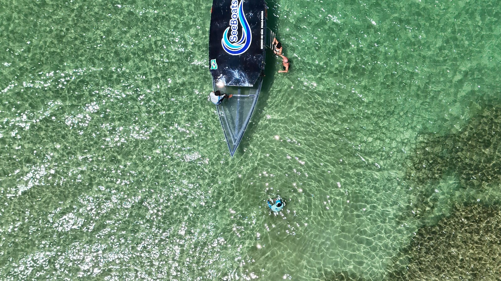 Lancha com fundo transparente navegando sobre águas verdes em Morro de São Paulo