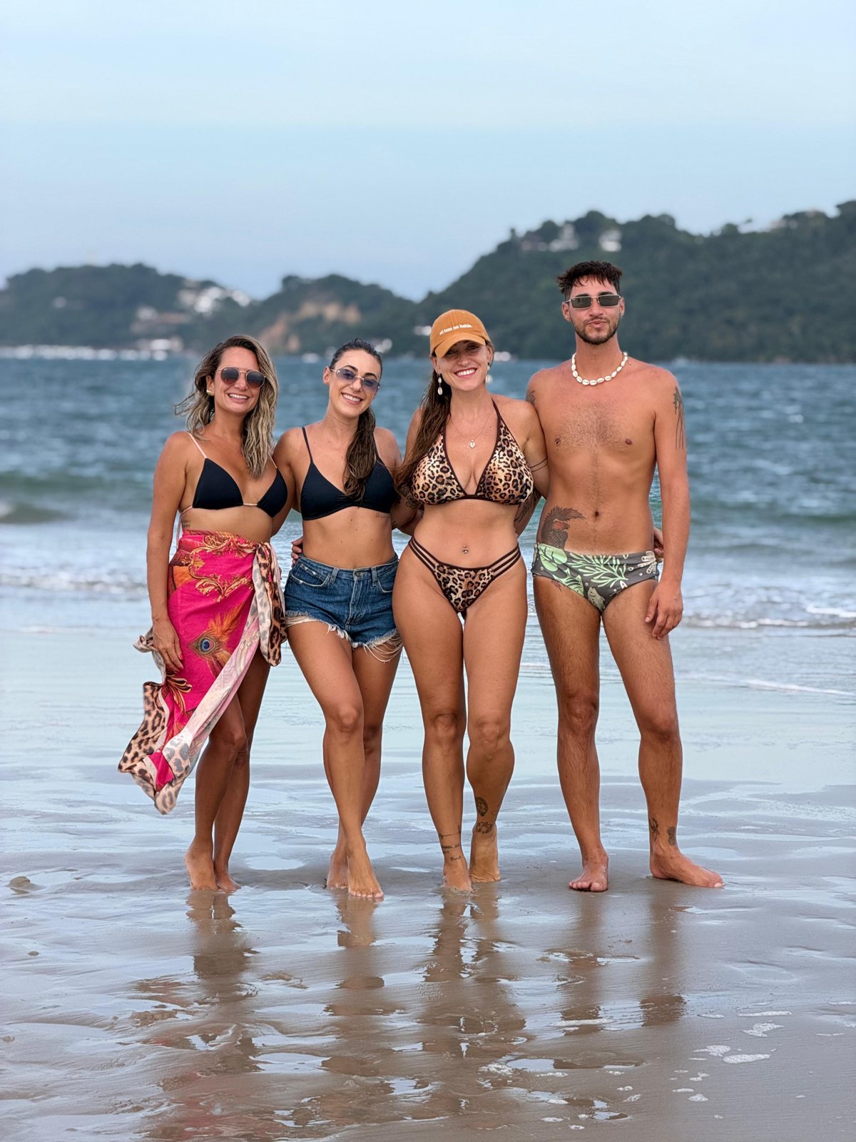 Grupo de amigos na areia de Morro de São Paulo com roupa leve, chapéu e mochila de praia